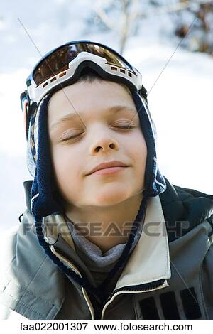Boy in ski gear smiling with eyes closed, high angle view View Large Photo Image Stock Photo - Boy in ski gear smiling with eyes closed, high angle view. Fotosearch