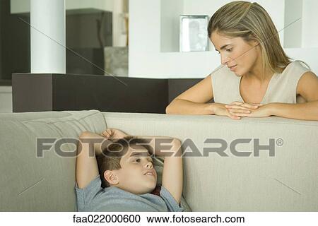 Boy lying on sofa talking to mother looking down at him View Large Photo Image Stock Image - Boy lying on sofa talking to mother looking down at him. Fotosearch