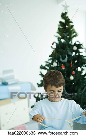 Stock Image - Boy opening Christmas presents. Fotosearch