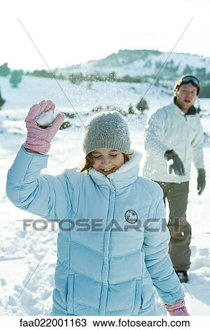 Stock Image - Brother and sister throwing snowballs, girl's eyes closed. Fotosearch