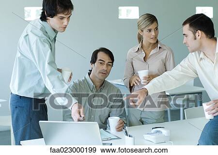 Business associates gathered around laptop, two pointing to screen View Large Photo Image Stock Photo - Business associates gathered around laptop, two pointing to screen. Fotosearch