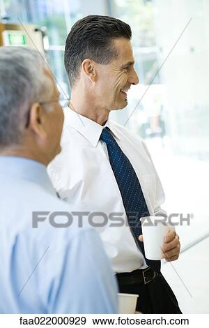 Business associates smiling, holding hot beverages, side view View Large Photo Image Stock Photo - Business associates smiling, holding hot beverages, side view. Fotosearch