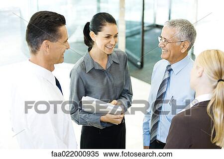 Business associates standing in lobby, smiling at each other, chatting View Large Photo Image Stock Photography - Business associates standing in lobby, smiling at each other, chatting. Fotosearch