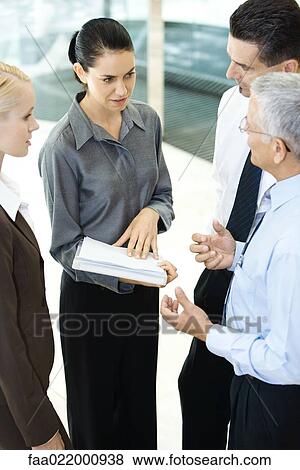 Stock Photo - Business associates standing together, discussing, high angle view. Fotosearch