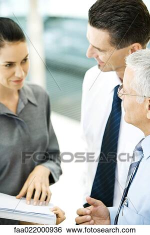 Stock Photograph - Business associates standing together, one holding file. Fotosearch