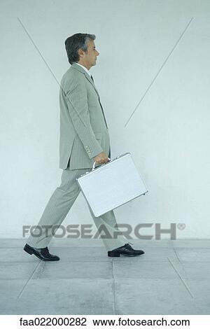 Businessman carrying briefcase, side view, full length portrait View Large Photo Image Stock Image - Businessman carrying briefcase, side view, full length portrait. Fotosearch