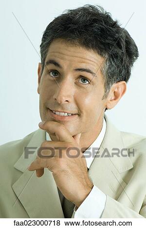 Businessman holding chin, looking up and smiling, portrait View Large Photo Image Stock Photo - Businessman holding chin, looking up and smiling, portrait. Fotosearch