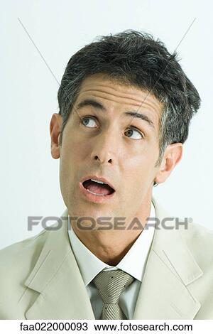 Stock Image - Businessman raising eyebrows, looking to the side, mouth open, portrait. Fotosearch