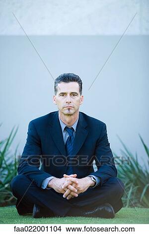 Businessman sitting on ground, looking at camera, full length portrait View Large Photo Image Picture - Businessman sitting on ground, looking at camera, full length portrait. Fotosearch