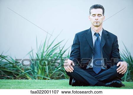 Businessman sitting on ground outdoors, meditating, eyes closed View Large Photo Image Stock Photo - Businessman sitting on ground outdoors, meditating, eyes closed. Fotosearch