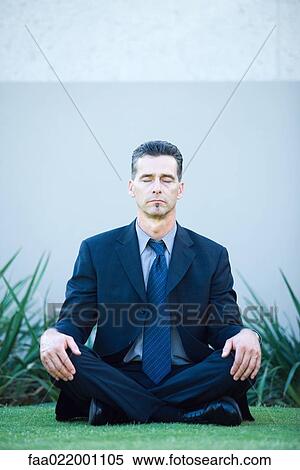 Stock Photography - Businessman sitting on ground, meditating, eyes closed, full length portrait. Fotosearch