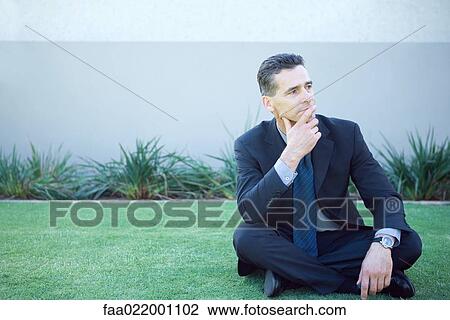 Businessman sitting on the ground outdoors, looking away, finger on lips View Large Photo Image Stock Image - Businessman sitting on the ground outdoors, looking away, finger on lips. Fotosearch