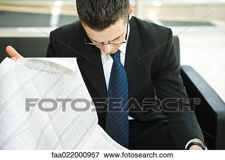 Stock Photo - Businessman sitting, reading newspaper, head down. Fotosearch