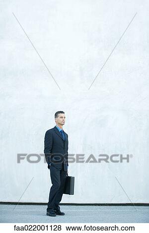 Businessman standing, looking away, full length portrait View Large Photo Image Stock Photo - Businessman standing, looking away, full length portrait. Fotosearch