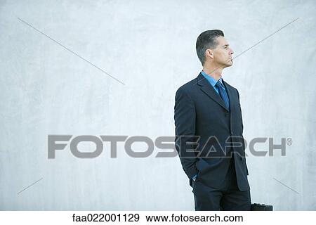 Businessman standing, looking away, hand in pocket View Large Photo Image Stock Photo - Businessman standing, looking away, hand in pocket. Fotosearch