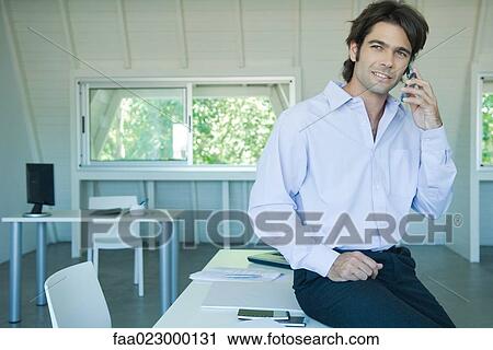 Businessman using cell phone in office, looking away View Large Photo Image Stock Image - Businessman using cell phone in office, looking away. Fotosearch