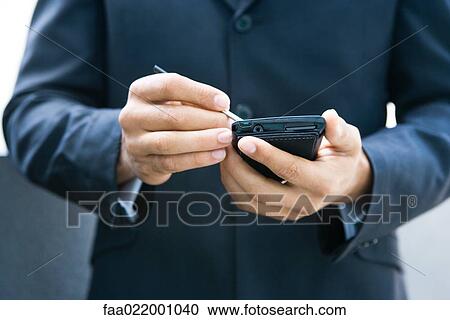 Stock Image - Businessman using palmtop, cropped view. Fotosearch