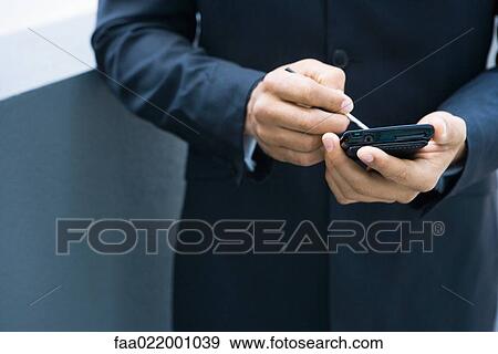 Stock Photo - Businessman using palmtop, cropped view of hands. Fotosearch