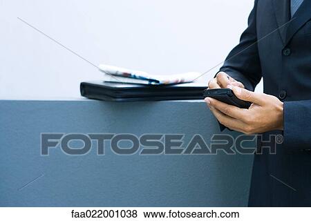 Stock Photo - Businessman using palmtop, side view, cropped view of hands. Fotosearch