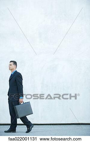 Businessman walking, carrying briefcase, full length View Large Photo Image Stock Image - Businessman walking, carrying briefcase, full length. Fotosearch
