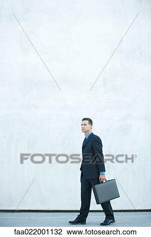 Businessman walking, carrying briefcase, full length View Large Photo Image Stock Image - Businessman walking, carrying briefcase, full length. Fotosearch