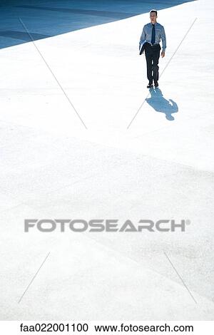 Businessman walking outdoors, full length, mid-distance View Large Photo Image Stock Image - Businessman walking outdoors, full length, mid-distance. Fotosearch