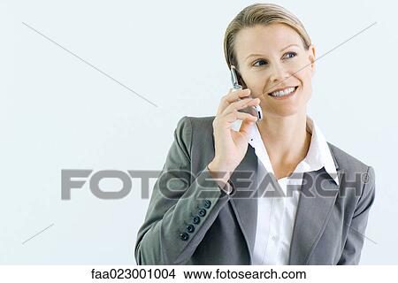 Picture - Businesswoman using cell phone, smiling, looking away. Fotosearch