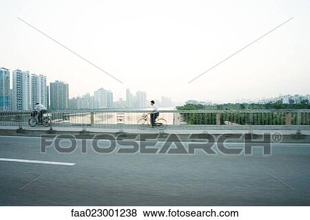 China, Guangdong Province, Guangzhou, cyclists crossing bridge, skyscrapers in distance View Large Photo Image Stock Photo - China, Guangdong Province, Guangzhou, cyclists crossing bridge, skyscrapers in distance. Fotosearch