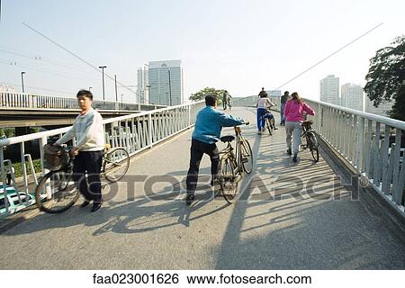 Stock Photograph - China, Guangdong Province, Guangzhou, cyclists crossing bridge. Fotosearch
