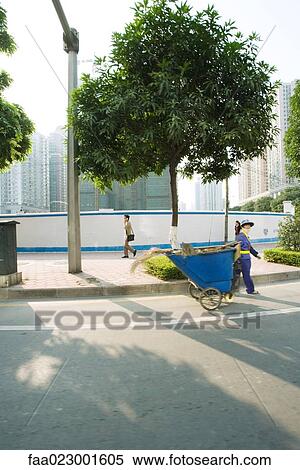 Stock Photography - China, Guangdong Province, Guangzhou, public maintenance worker pulling bin through street. Fotosearch