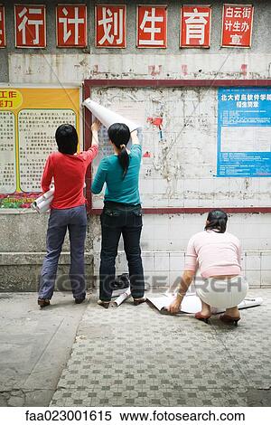 China, Guangdong Province, Guangzhou, young women hanging posters on wall View Large Photo Image Stock Photography - China, Guangdong Province, Guangzhou, young women hanging posters on wall. Fotosearch