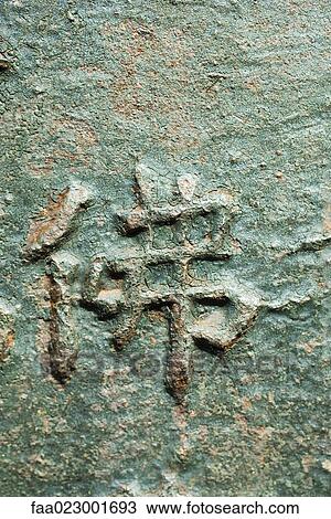 Stock Image - Chinese characters in relief on bronze surface, close-up. Fotosearch