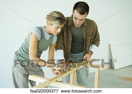 Stock Photo - Couple making measurements on wood plank. Fotosearch