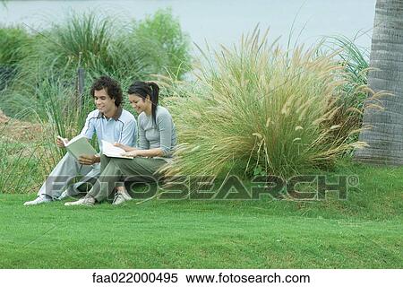 Stock Photography - Couple sitting on grass, reading books. Fotosearch