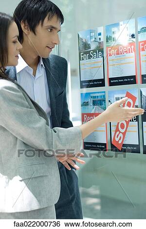Couple standing next to window of real estate agency, looking at for rent and for sale signs View Large Photo Image Stock Photograph - Couple standing next to window of real estate agency, looking at for rent and for sale signs. Fotosearch