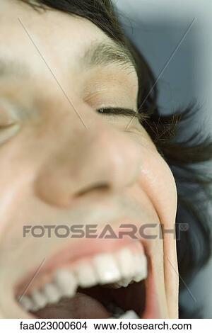 Picture - Cropped view of teenage boy laughing, eyes closed, extreme close-up. Fotosearch