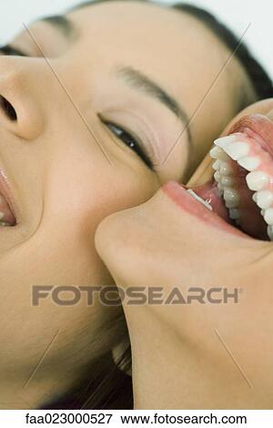 Cropped view of two young friends laughing together, one looking at camera, extreme close-up View Large Photo Image Stock Photo - Cropped view of two young friends laughing together, one looking at camera, extreme close-up. Fotosearch