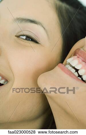 Cropped view of two young friends laughing together, one looking at camera, extreme close-up View Large Photo Image Stock Photo - Cropped view of two young friends laughing together, one looking at camera, extreme close-up. Fotosearch