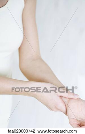 Cropped view of woman holding wrist, close-up View Large Photo Image Stock Image - Cropped view of woman holding wrist, close-up. Fotosearch