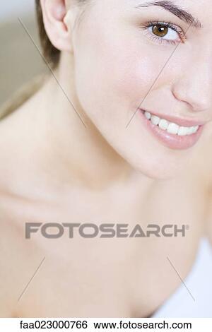 Stock Photograph - Cropped view of young woman, smiling at camera, portrait. Fotosearch