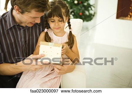 Father and daughter opening present together, Christmas tree in background View Large Photo Image Stock Photo - Father and daughter opening present together, Christmas tree in background. Fotosearch