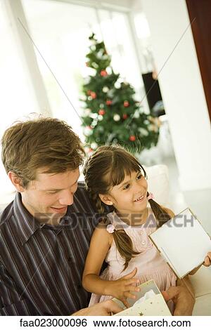 Father and daughter opening present together, Christmas tree in background View Large Photo Image Stock Photograph - Father and daughter opening present together, Christmas tree in background. Fotosearch