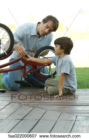 Father and son fixing bike together View Large Photo Image Stock Photo - Father and son fixing bike together. Fotosearch