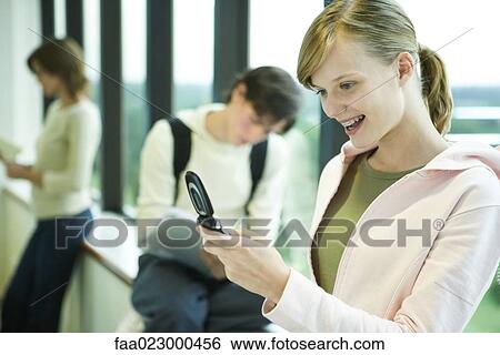 Female college student looking at cell phone, smiling View Large Photo Image Stock Photograph - Female college student looking at cell phone, smiling. Fotosearch