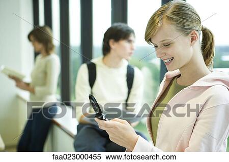 Female college student looking at cell phone, smiling View Large Photo Image Stock Photography - Female college student looking at cell phone, smiling. Fotosearch