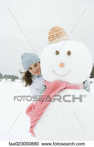 Stock Image - Female embracing snowman, smiling at camera, portrait. Fotosearch