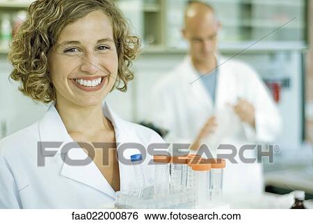 Female lab worker holding rack of empty test tubes, smiling at camera, portrait View Large Photo Image Stock Photograph - Female lab worker holding rack of empty test tubes, smiling at camera, portrait. Fotosearch