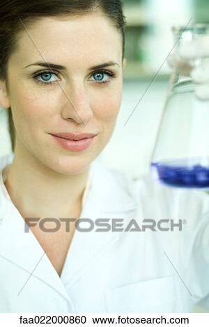 Female lab worker holding up flask, looking at camera, portrait View Large Photo Image Stock Image - Female lab worker holding up flask, looking at camera, portrait. Fotosearch