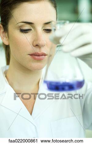 Female lab worker holding up flask, inspecting its contents View Large Photo Image Stock Image - Female lab worker holding up flask, inspecting its contents. Fotosearch