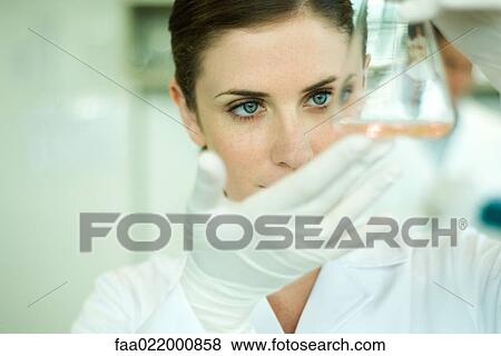Female lab worker holding up flask View Large Photo Image Stock Photo - Female lab worker holding up flask. Fotosearch